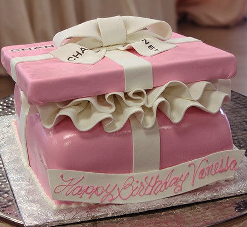 The BD-027F Gift box pink cake is decorated as a pink and white gift box with a bow on top, features ruffled icing, and has “Happy Birthday Vanessa” written in pink icing on the side.