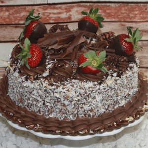The BD-018L German Chocolate with pecan and coconut is a round cake topped with chocolate shavings, pecan-coconut frosting, and displayed on a white cake stand against a rustic wooden background.