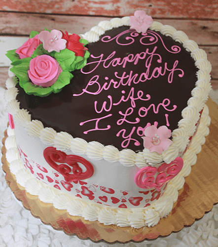 Heart-shaped cake (VC-011) with chocolate glaze, pink and white icing, floral roses and hearts, and "Happy Birthday Wife, I Love You!" written on top.