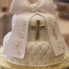 Product TC-021: White fondant cake with a large bow, gold cross, quilted design, "God Bless" and "Sonia" in gold on two ribbons, presented on a gold cake board.
