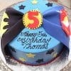 The CB-006D is a blue birthday cake with Batman and Superman logos, a large red number 5, yellow and black stars, and "Happy 5th Birthday Thomas" written in black icing.