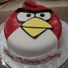 Our CB-011K is a round cake styled as the red Angry Bird with fondant, a yellow beak, and black eyebrows. It sits on a silver base with "Happy 10th Birthday Braden" piped in red icing.