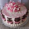 BB-007 is a round cake with pink and white frosting roses, a large pink ribbon, and chocolate teddy bears. The piped message reads "Congratulations on Your Baby Girl!".