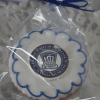 The GC-080C Quincy High School is a round cookie with white icing and a blue scalloped border, wrapped in clear plastic with a blue ribbon. The center features the Quincy High School logo.