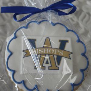 A round GC-080F Archbishop Williams High School cookie with blue icing and a blue-and-gold BISHOPS/W emblem, wrapped in clear plastic and tied with a blue ribbon.