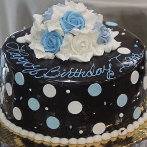 The BD-078 is a round chocolate cake decorated with white and light blue polka dots, topped with white and blue icing roses, and features "Happy Birthday" written in blue icing on top.