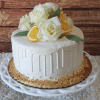 The BR-004 cake features white frosted icing with a white drip, topped with white roses, orange slices, and green leaves. Chopped nuts border the base, and it's displayed on a white decorative stand.