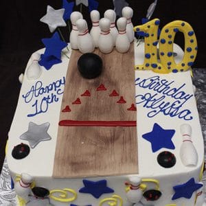 The ST-008 Bowling Blue/Silver is a square birthday cake featuring a bowling lane, pins, balls, stars, a large yellow 10, and "Happy 10th Birthday Alysha" written in blue icing.