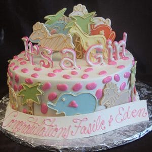 The BB-032 is a round white cake with pink polka dots, pastel animal-shaped cookies, and "It's a Girl" on top. A plaque at the base says "Congratulations Fasie & Eden" in pink script.