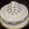 AN-020: A round white cake with “Happy 50th Anniversary” in gold icing, topped with white and gold ribbon loops, and finished with a brown ribbon and white bows around the sides.