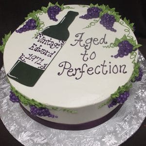 The BD-024P VintageWine cake features purple grapes and a wine bottle design, with the message "Aged to Perfection" and "Vintage Edward 1971," presented on a silver board.