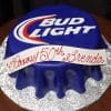 The BD-025 Bud Light is a round cake designed as a blue Bud Light can, featuring the logo on top and a white banner with "Happy 50th Brenda" in red script, set on a silver patterned board.