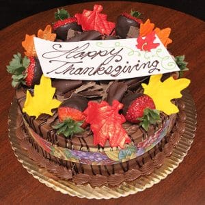 The THX-003 Display Chocolate Cake features chocolate mousse filling, fall-themed fondant leaves, chocolate-covered strawberries, and a "Happy Thanksgiving" white plaque, presented on a gold tray.