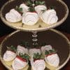 The ST-006-White Chocolate Strawberries are displayed on a two-tiered gold tray, each berry dipped in white chocolate with a milk chocolate drizzle and set in white paper cups on both tiers.