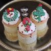 A gold cupcake (Product: CC-078) with chocolate mousse filling is displayed with festive Christmas decor, featuring holiday designs like a wreath, stocking, and Christmas tree on a silver tray.
