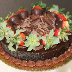 The CH-048 Chocolate Decadence Gluten Free cake features chocolate shavings, chocolate-covered strawberries, and fresh strawberries with green leaves on a gold cake board.