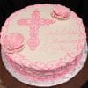 RC-025: Round cake with pink icing, large cross, two pink flowers, and “God Bless Carmelina Louise” in cursive on top. Presented on a foil-covered round board.