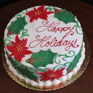 CH-019: A round cake with white frosting, decorated with red poinsettias, green holly leaves, and "Happy Holidays" in red icing, displayed on a gold-colored tray.