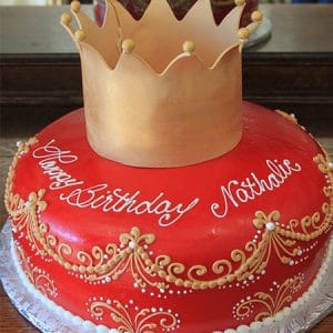 The BD-056A is a round red birthday cake with gold designs, white dots, and a large gold crown on top. “Happy Birthday Nathalie” is written in white icing.