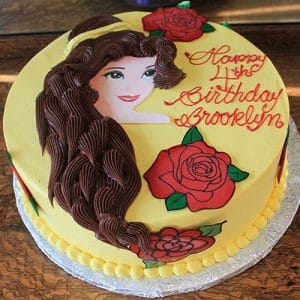 CB-008F: Round birthday cake with yellow icing, Belle (Beauty and the Beast) face, brown chocolate hair, red roses, and “Happy 4th Birthday Brooklyn” written in red on top.