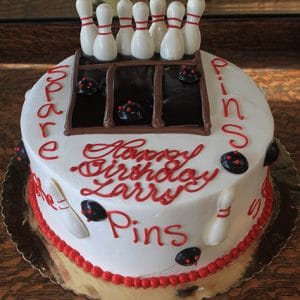 The ST-008 Bowling Red/Brown is a round birthday cake decorated with red icing words "Happy Birthday Larry, Pins, Spare" and features a chocolate bowling lane with fondant pins and balls.