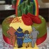 The CB-010C cake features Dorothy, the Tin Man, Scarecrow, and Cowardly Lion on a yellow brick road to emerald towers, topped with red ruby slippers and a rainbow for a Wizard of Oz theme.