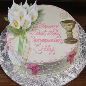 RC-008: A round white cake decorated with pink and gold accents, calla lilies, a gold chalice, pink crosses, and "Happy First Holy Communion Lilly" written in pink icing.