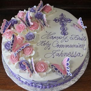 The RC-026 is a round white cake with pink and purple roses, butterfly toppers, and a purple cross. "Happy First Holy Communion Jahnessa" appears in purple script icing.