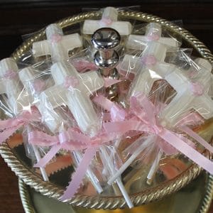 RC-116 features white cross-shaped lollipops wrapped in plastic and tied with pink ribbons, beautifully arranged on a two-tiered silver tray—perfect for religious celebrations or events.