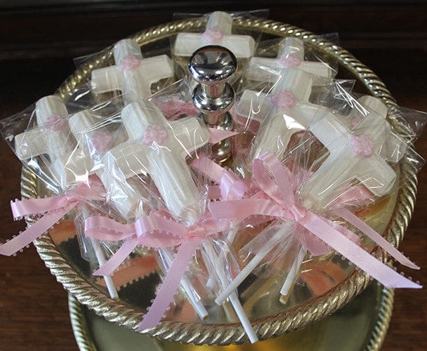 RC-116 features white cross-shaped lollipops wrapped in plastic and tied with pink ribbons, beautifully arranged on a two-tiered silver tray—perfect for religious celebrations or events.