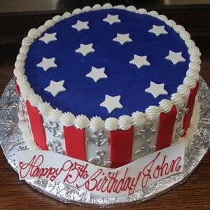 The JC-012 is a round cake with red and white vertical stripes, silver anchors, a blue top with white stars, and a front plaque that says "Happy 75th Birthday John.