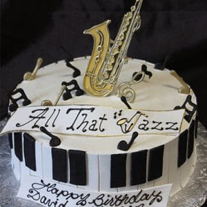 BD-063 Saxophone/piano/music notes: A round cake featuring piano keys, edible musical notes, a golden saxophone topper, and "All That Jazz" with "Happy Birthday David Johnson" written in black script.