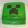 A square green CB-011F cake decorated as a Minecraft Creeper face with "Happy Birthday Daniel!" in black icing on the front, displayed on a white patterned board.