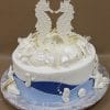 Product AN-014: A round cake topped with two large seahorses and white chocolate seashells. The bottom tier is covered in blue and white fondant, accented with extra seashell and seahorse decorations.