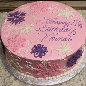 The CH-037 is a round pink birthday cake with white, pink, and purple floral designs and "Happy 17th Birthday Varnai" written in purple icing, presented on a silver board.