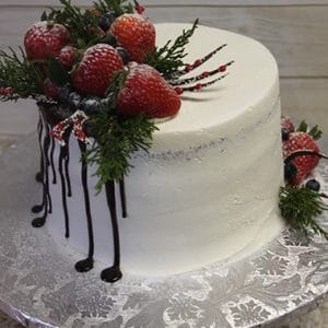 The CH-026 is a white frosted cake with strawberries, blueberries, greenery, and a dark chocolate drip on one side, presented on a silver floral-patterned cake board.