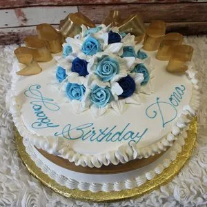 The AN-005 is a round white birthday cake with blue and white icing roses, gold ribbon accents, and "Happy Birthday Dana" in blue script. The cake is presented on a gold board.