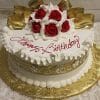 The AN-002A is a round birthday cake with white icing, gold ribbon accents, and red and white fondant roses on top. "Happy Birthday" in red script decorates the cake, which sits on a gold floral-patterned board.