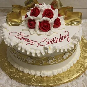 The AN-002A is a round birthday cake with white icing, gold ribbon accents, and red and white fondant roses on top. "Happy Birthday" in red script decorates the cake, which sits on a gold floral-patterned board.