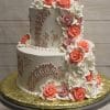The WC-000E is a two-tiered white cake with lace-like piping and cascading buttercream roses in pink, coral, and white, presented on a gold-covered cake board atop a gray cake stand.