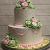 The TC-001 is a two-tiered white cake adorned with pink and white icing roses, green leaves, and pink dots and scalloped lines. It rests on a gold-colored board against a wooden background.