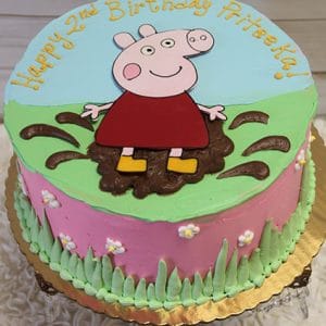 The CB-009D is a round birthday cake featuring Peppa Pig in a muddy puddle, pink and green icing, small flowers, and "Happy 2nd Birthday Priteeha!" written on top in yellow.