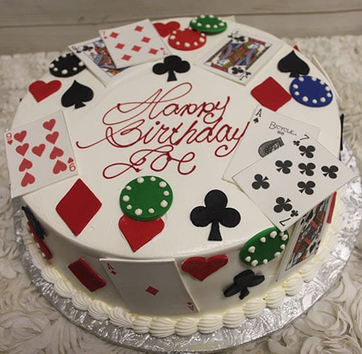 The GR-012 is a round birthday cake with playing cards, poker chips, and card suit symbols, topped with "Happy Birthday" in red icing. It sits on a silver board with piped white frosting around the edge.