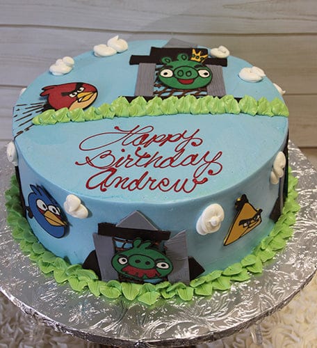 CB-011J is a round blue birthday cake with green icing trim, Angry Birds characters, and "Happy Birthday Andrew" in red icing on top. White fondant clouds and character faces decorate the sides.