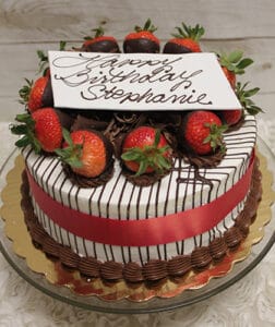 The BD-001 cake features chocolate-dipped strawberries, chocolate drizzle, a red ribbon, and a white "Happy Birthday Stephanie" plaque in cursive. Choose your preferred flavor. Presented on a gold tray.
