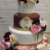 WD-090 features three tiers with gold accents, burgundy and white layers, pink and cream flowers, gold drip details, a marbled pink bottom tier, and a gold monogram "L" on the middle tier.