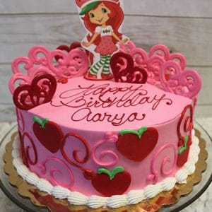 The SC-027 Strawberry Shortcake is a pink birthday cake with red hearts, pink swirls, a cartoon girl in a strawberry outfit topper, and "Happy Birthday Aarya" written in red icing.