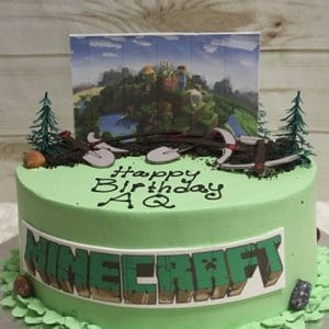 The CB-011H is a round green Minecraft-themed birthday cake with toy trees, rocks, a Minecraft scene topper, "Happy Birthday AQ" in black icing on top, and "MINECRAFT" printed on the side.