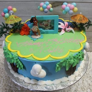 The SC-018 Moana birthday cake features vibrant decorations like palm trees, flowers, balloons, umbrellas, and Moana and Pua figurines. "Happy 5th Birthday Nishii" is written in pink.