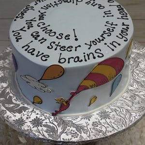 The BB-075 is a round cake adorned with colorful balloons, clouds, whimsical designs, and topped with the Dr. Seuss quote: "You have brains in your head. You have feet in your shoes. You can steer yourself in any direction you choose!.